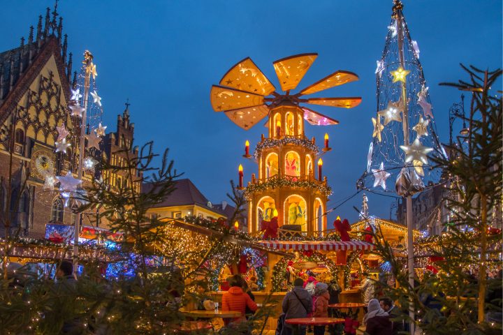 Et levende julemarked i Polen, oplyst af festlige lys og fyldt med besøgende, der nyder traditionelle lækkerier